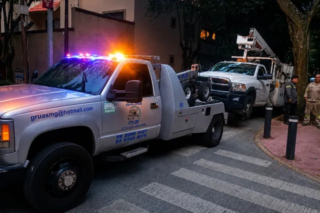 Unidad de arrastre de Grúas MG trabajando de noche en calle de la Ciudad de México