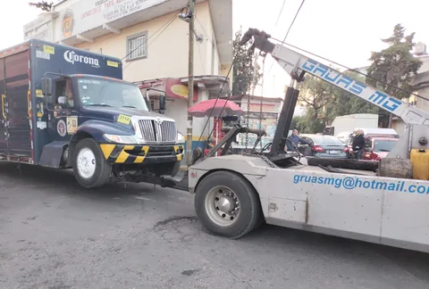 Camión de reparto de Corona enganchado a la grúa de arrastre de Grúas MG