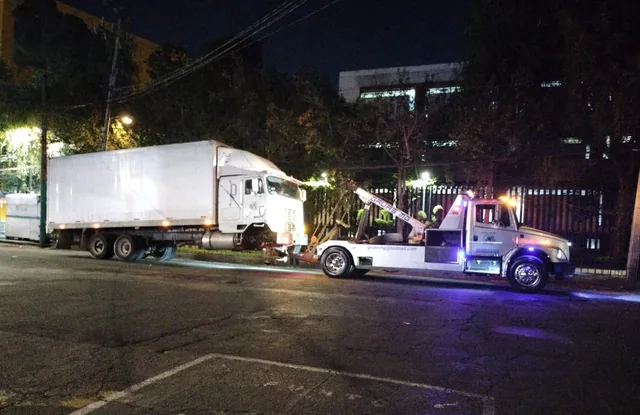 Tráiler con caja remolcado de noche por la grúa de arrastre de Grúas MG en calle de la Ciudad de México